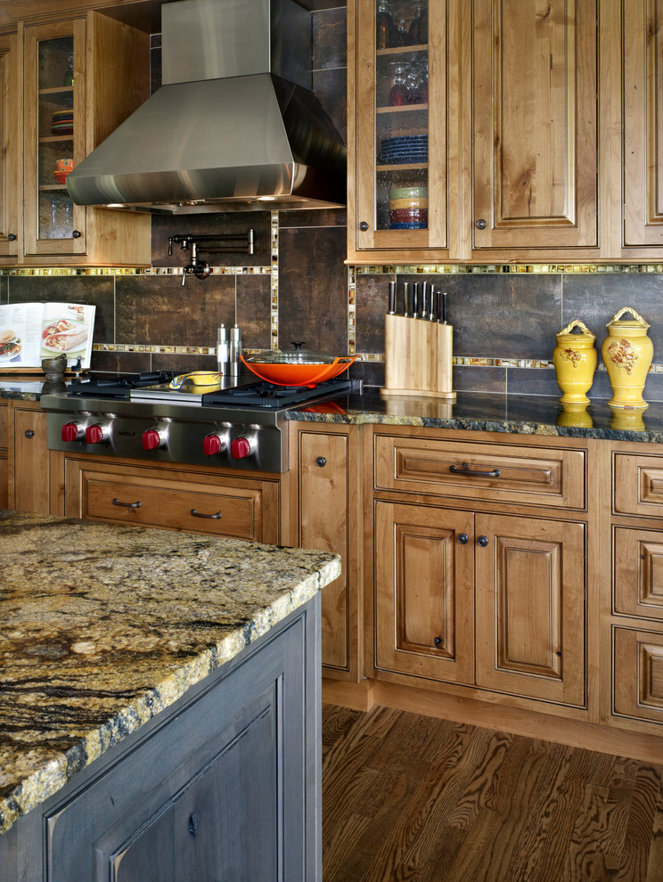 Large mountain style l-shaped medium tone wood floor open concept kitchen photo in Denver with a double-bowl sink, raised-panel cabinets, light wood cabinets, granite countertops, brown backsplash, porcelain backsplash, stainless steel appliances and an island