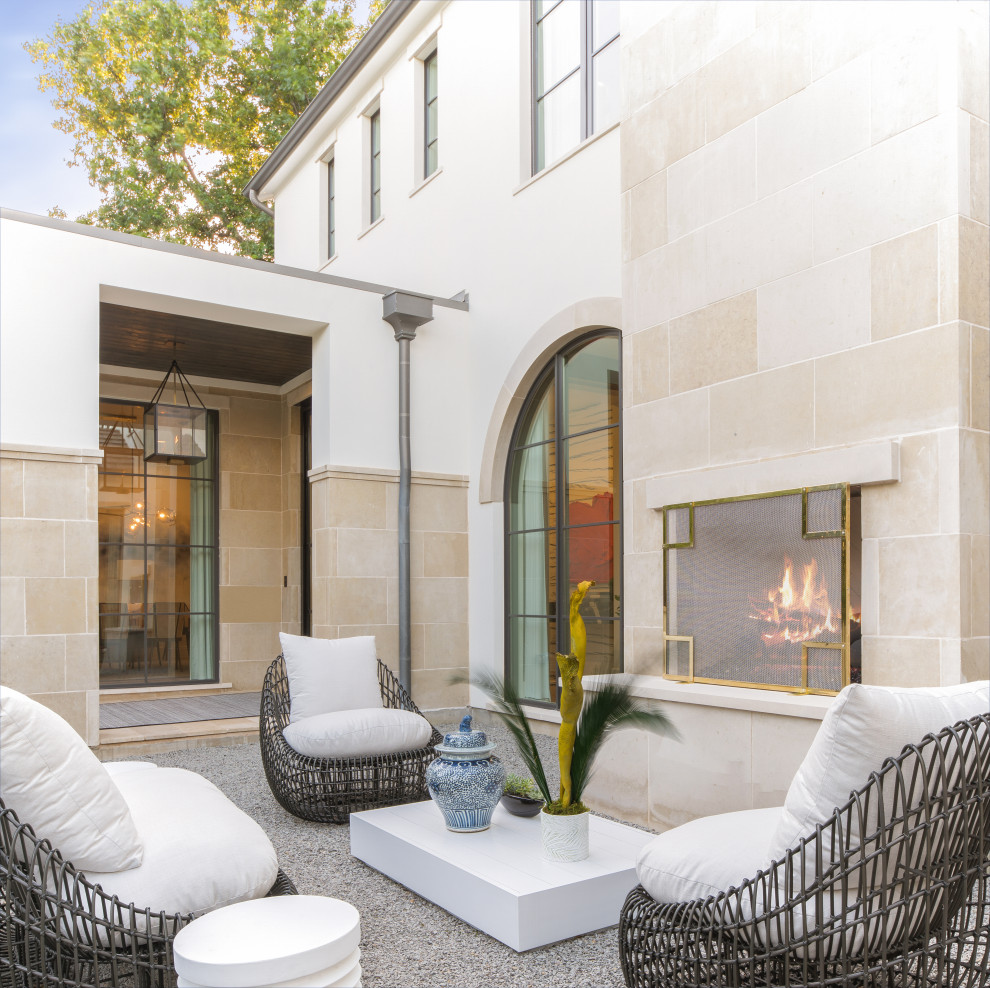 This is an example of a mediterranean courtyard patio in Dallas with with fireplace, gravel and no cover.