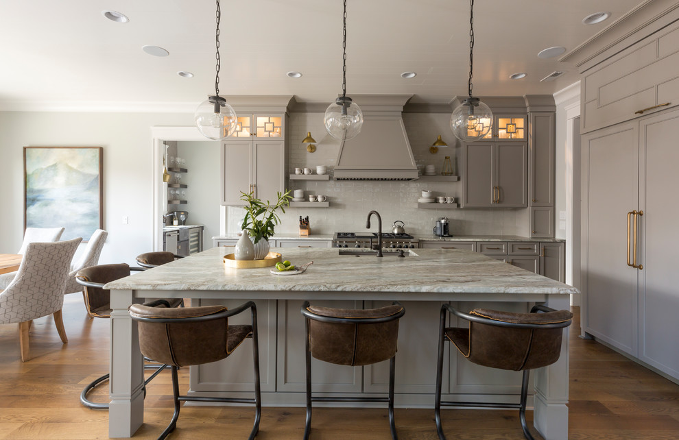 Inspiration for a transitional l-shaped eat-in kitchen in Charlotte with an undermount sink, recessed-panel cabinets, grey cabinets, white splashback, panelled appliances, medium hardwood floors, with island, brown floor and beige benchtop.