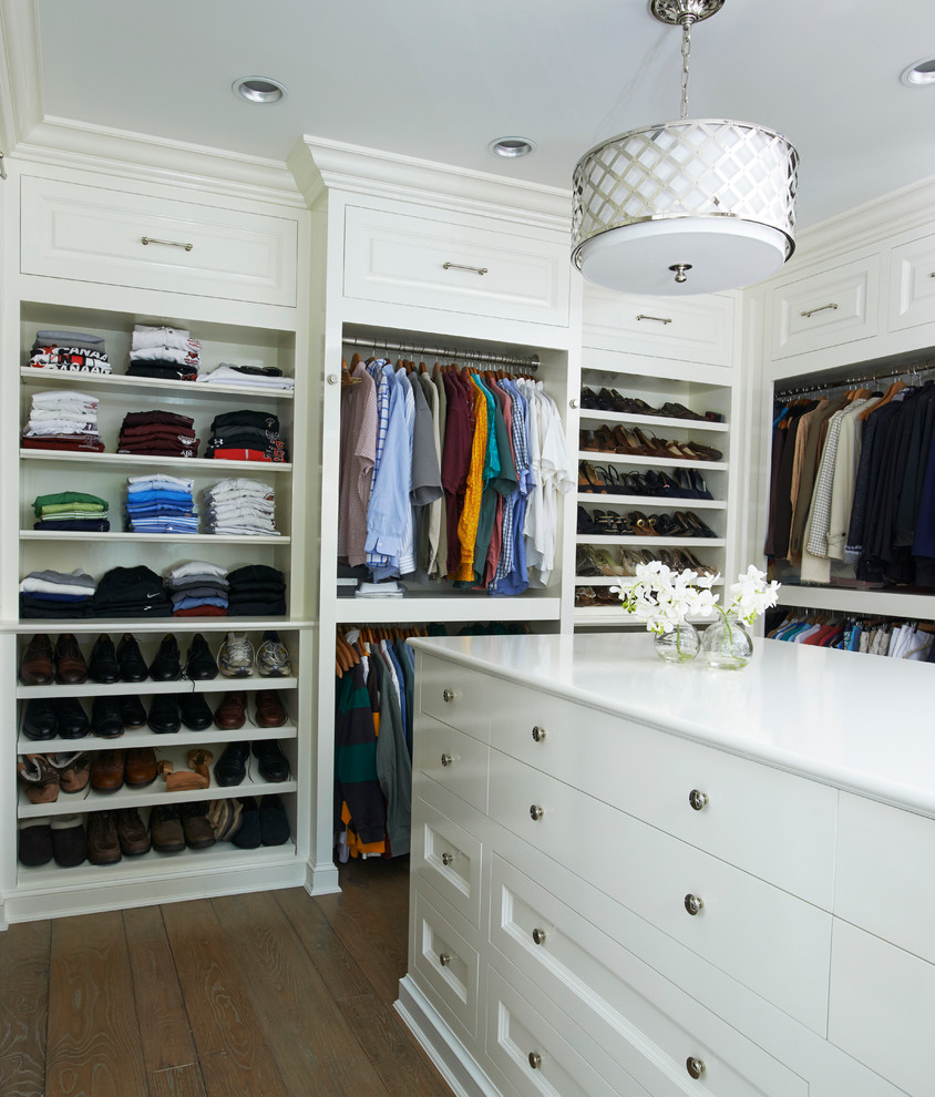 Large traditional gender-neutral walk-in wardrobe in New York with white cabinets, flat-panel cabinets, dark hardwood floors and brown floor.