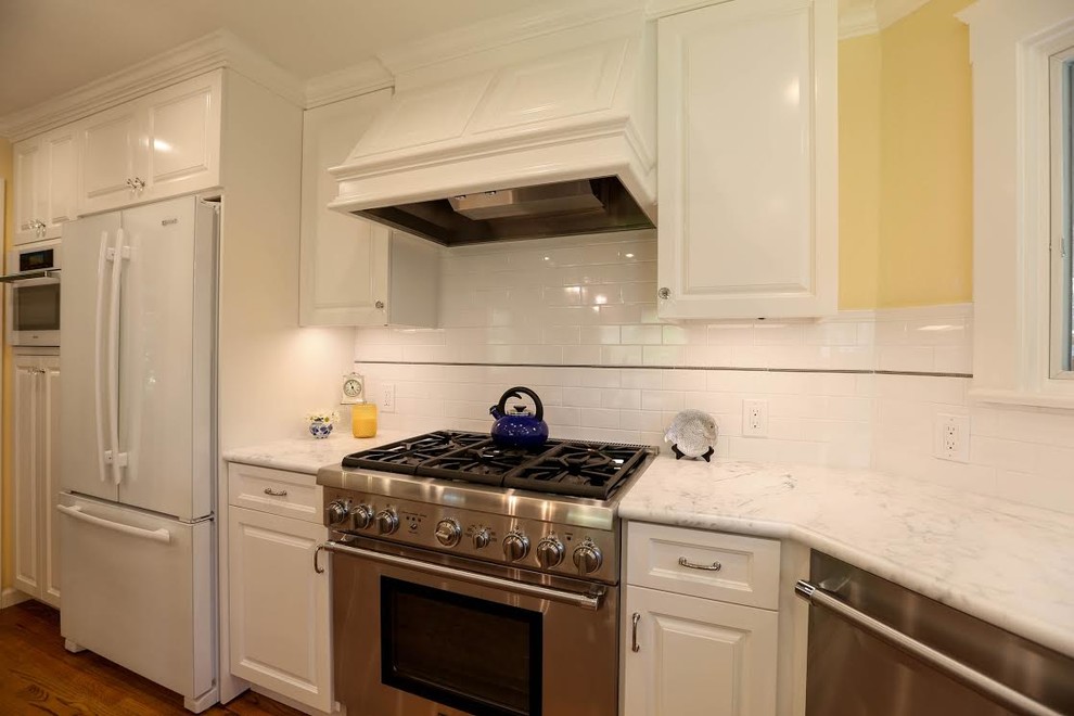 Mid-sized transitional u-shaped light wood floor enclosed kitchen photo in San Francisco with an undermount sink, beaded inset cabinets, white cabinets, marble countertops, white backsplash, subway tile backsplash, white appliances and an island