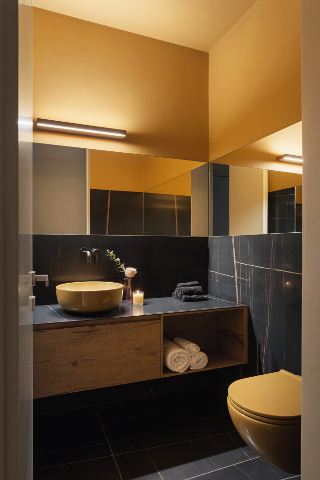 Пример оригинального дизайна: маленькая ванная комната в современном стиле с плоскими фасадами, бежевыми фасадами, инсталляцией, черной плиткой, мраморной плиткой, желтыми стенами, мраморным полом, настольной раковиной, мраморной столешницей, черным полом, черной столешницей, тумбой под одну раковину и подвесной тумбой для на участке и в саду