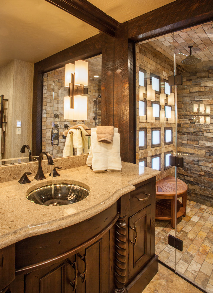 Photo of a mid-sized country master bathroom in Other with recessed-panel cabinets, dark wood cabinets, a curbless shower, a two-piece toilet, beige tile, stone tile, beige walls, travertine floors, an undermount sink and engineered quartz benchtops.