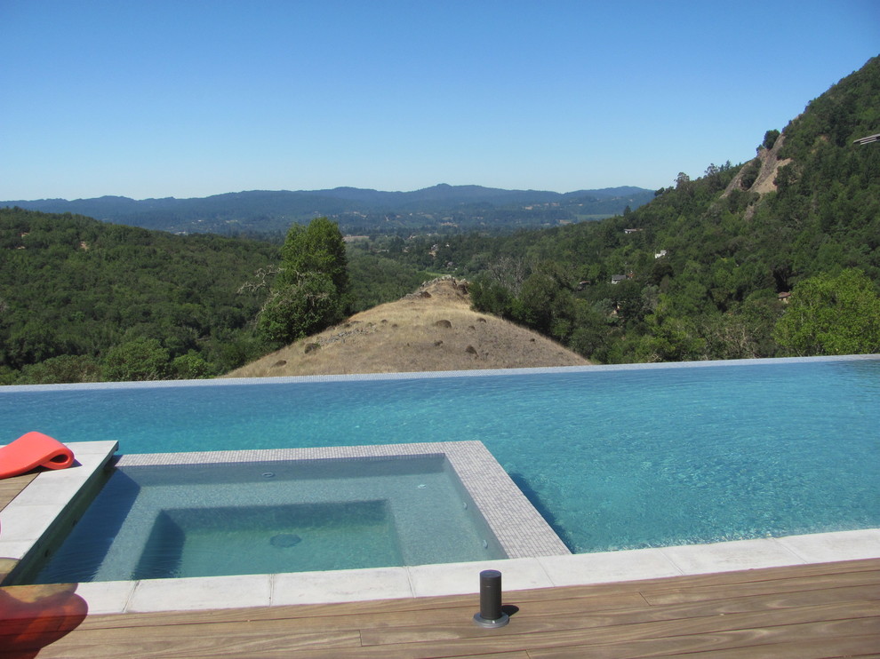 Inspiration for a mid-sized modern backyard rectangular infinity pool in San Francisco with a hot tub and decking.