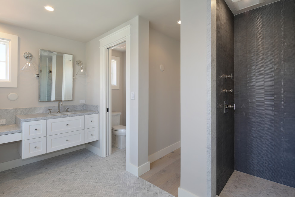 Photo of a mid-sized beach style master bathroom in Orange County with shaker cabinets, white cabinets, an alcove shower, a two-piece toilet, black tile, grey walls, marble floors, an undermount sink, marble benchtops, grey floor, an open shower and grey benchtops.