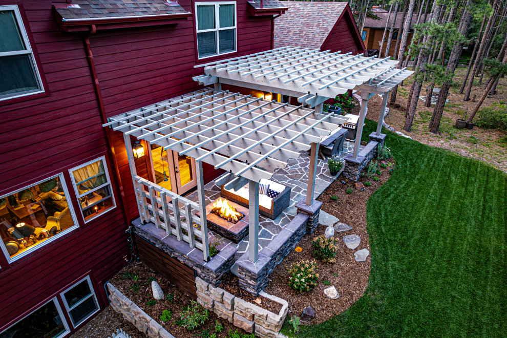 Diseño de patio tradicional de tamaño medio en patio trasero con brasero, adoquines de piedra natural y pérgola
