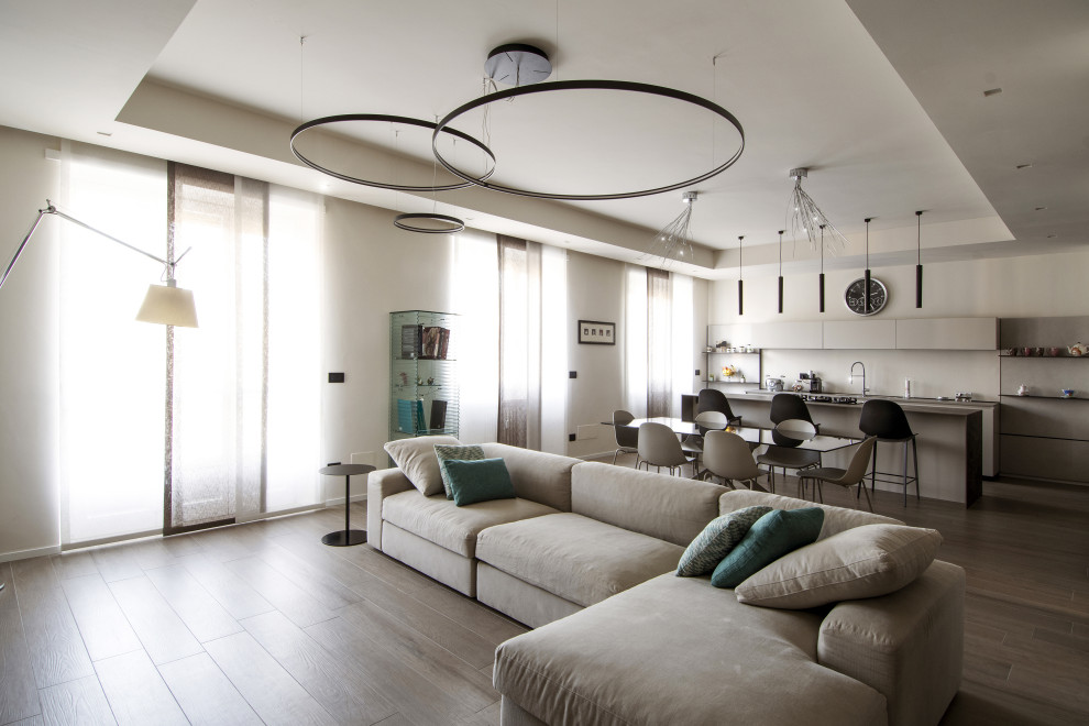This is an example of an expansive contemporary open concept living room in Turin with white walls, porcelain floors, a wall-mounted tv and brown floor.