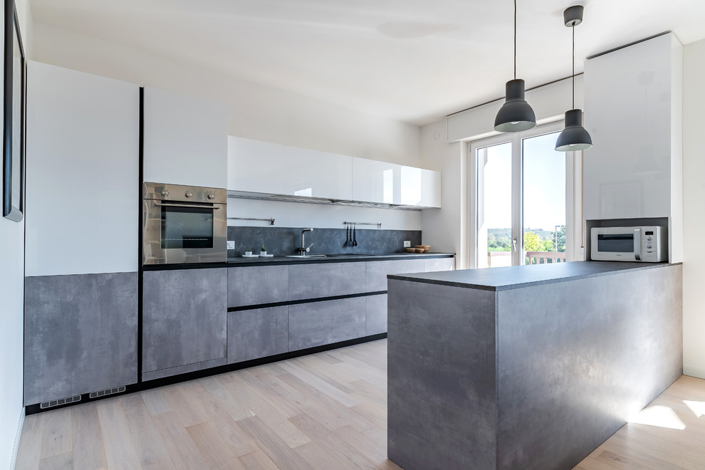 Design ideas for a mid-sized contemporary single-wall open plan kitchen in Other with a drop-in sink, flat-panel cabinets, grey cabinets, laminate benchtops, grey splashback, stainless steel appliances, light hardwood floors, with island and grey benchtop.