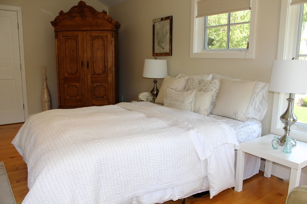 Inspiration for a large beach style guest bedroom in Boston with beige walls and light hardwood floors.