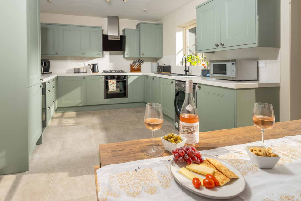 Eat-in kitchen - large u-shaped ceramic tile and beige floor eat-in kitchen idea with shaker cabinets, green cabinets, quartz countertops, white backsplash, stainless steel appliances, no island and white countertops