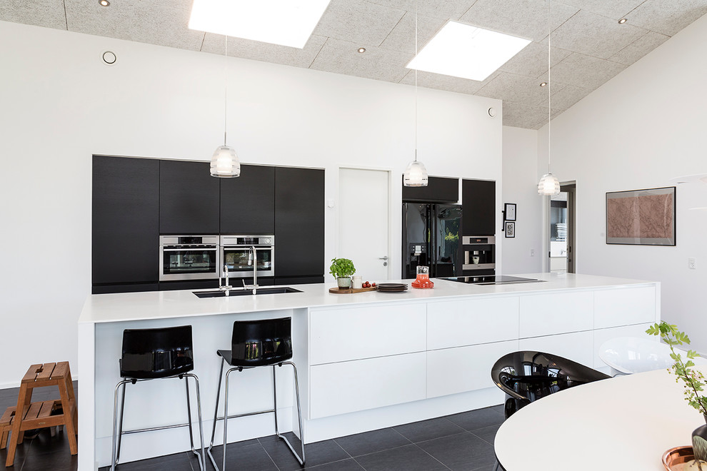 Design ideas for a large contemporary galley eat-in kitchen in Aarhus with with island, flat-panel cabinets, black cabinets, an undermount sink, slate floors and stainless steel appliances.
