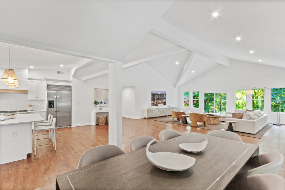 Photo of a large contemporary open plan dining room in New York with white walls, medium hardwood flooring and a vaulted ceiling.