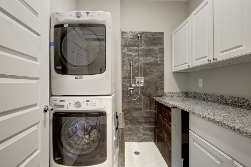 Photo of a mid-sized transitional utility room in DC Metro with raised-panel cabinets, white cabinets, beige walls, ceramic floors and a stacked washer and dryer.