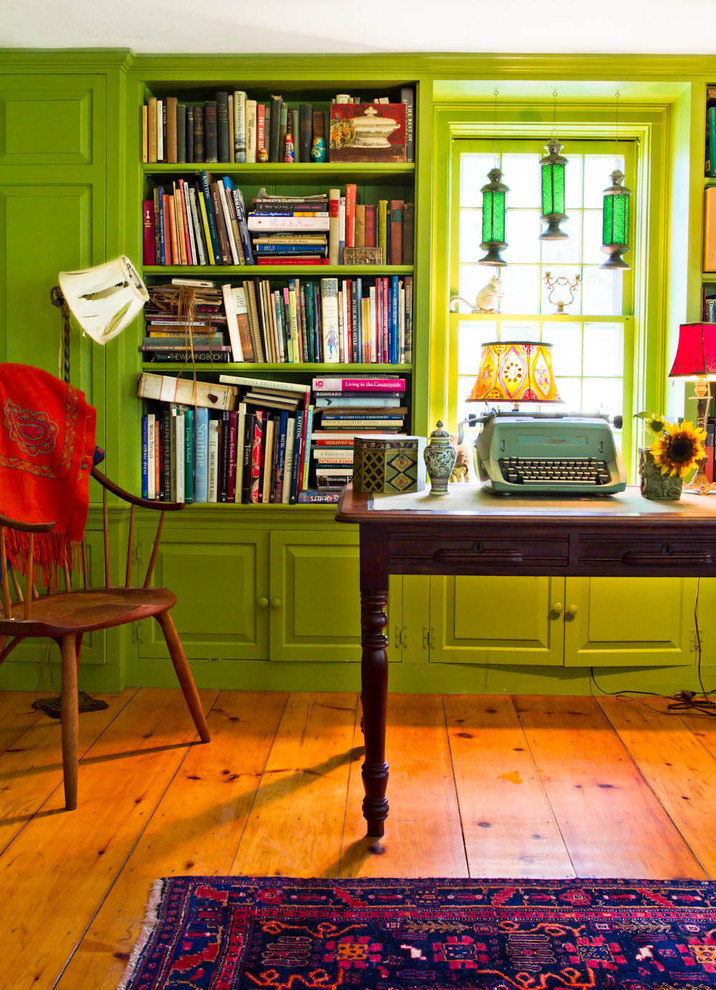This is an example of a country home office in New York with green walls and brown floor.