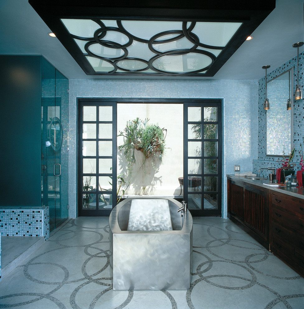 Inspiration for a large transitional master bathroom in Orange County with louvered cabinets, dark wood cabinets, a freestanding tub, a corner shower, blue tile, mosaic tile, blue walls, an undermount sink, solid surface benchtops, grey floor and a hinged shower door.