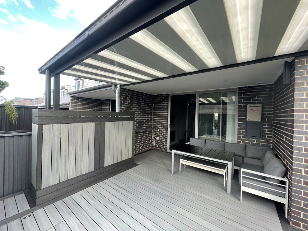 This is an example of a mid-sized backyard and ground level deck in Sydney with a pergola.