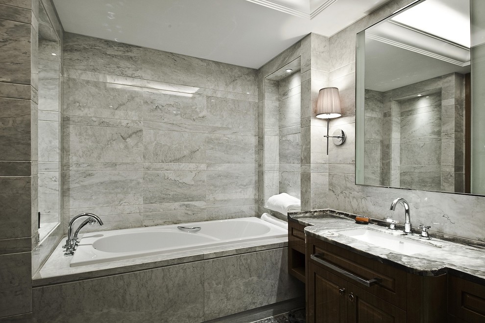 This is an example of a mid-sized traditional master bathroom in Other with an undermount sink, furniture-like cabinets, brown cabinets, marble benchtops, an undermount tub, a double shower, a one-piece toilet, gray tile, stone tile, grey walls and marble floors.