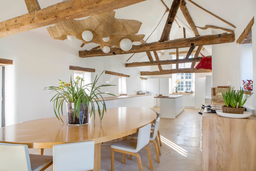 Country kitchen/dining combo in Oxfordshire with white walls and travertine floors.