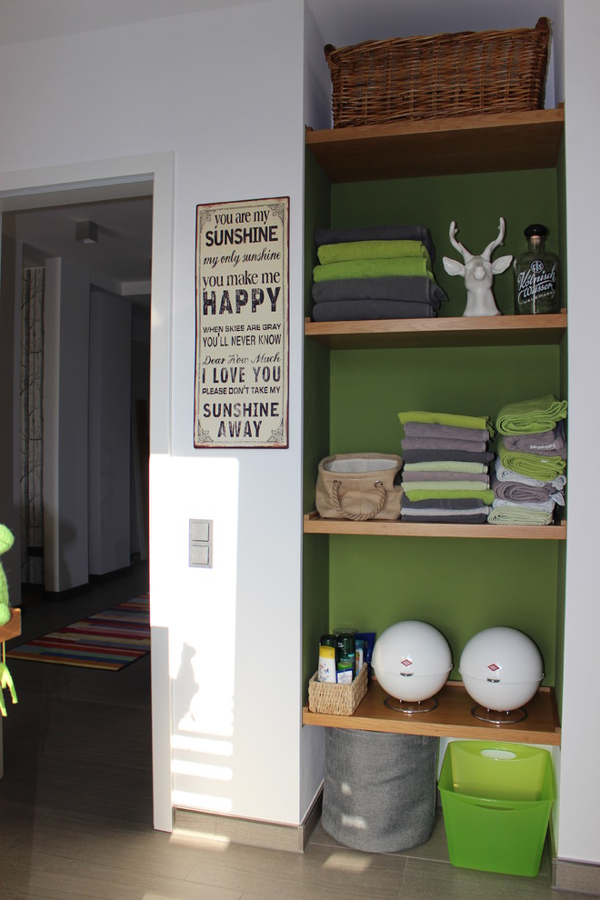 Mittelgroße Moderne Gästetoilette mit offenen Schränken, hellbraunen Holzschränken, Wandtoilette mit Spülkasten, grauen Fliesen, Keramikfliesen, weißer Wandfarbe und Einbauwaschbecken in Dortmund