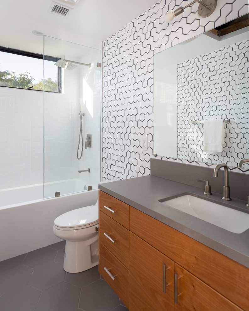 Contemporary 3/4 bathroom in Los Angeles with flat-panel cabinets, medium wood cabinets, an alcove tub, a shower/bathtub combo, black and white tile, an undermount sink, grey floor, an open shower and grey benchtops.
