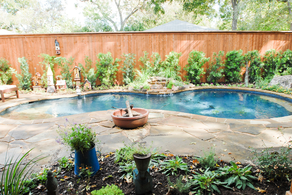 This is an example of a mid-sized traditional backyard kidney-shaped pool in Dallas with a water feature and natural stone pavers.