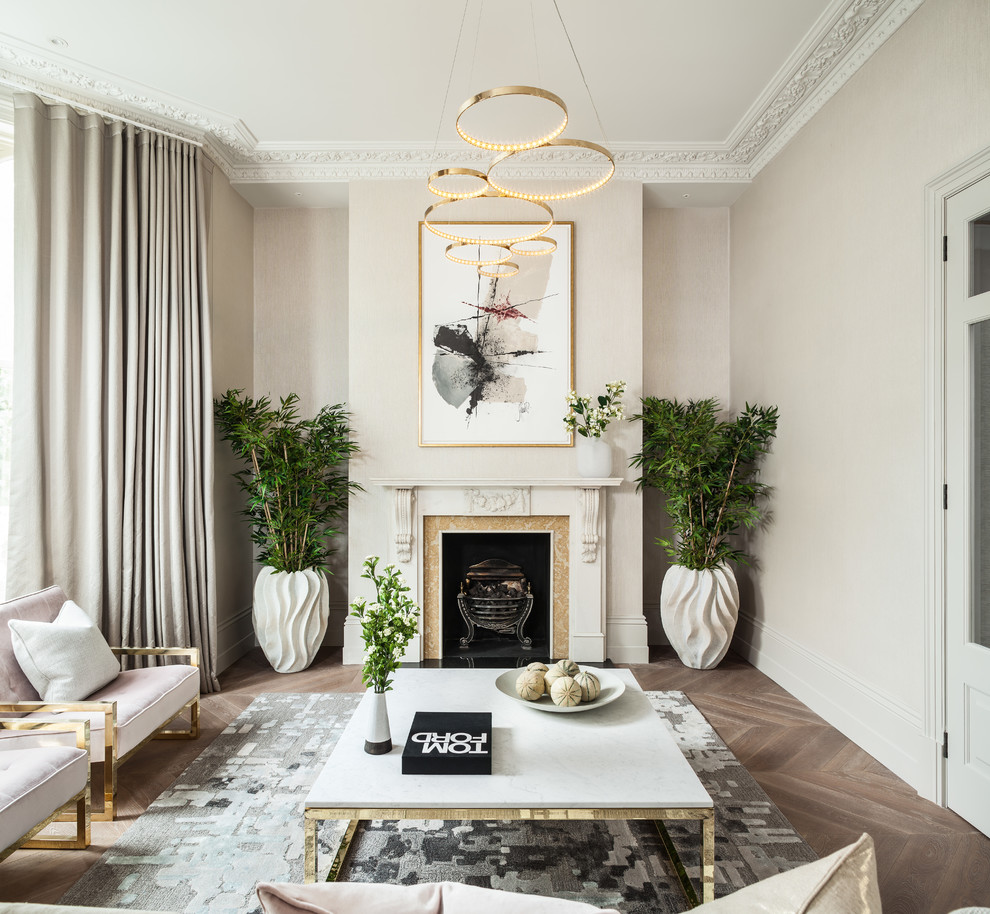 Design ideas for a mid-sized transitional enclosed living room in London with beige walls, medium hardwood floors, a standard fireplace and brown floor.