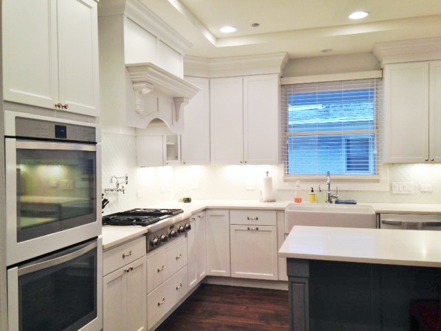 Inspiration for a mid-sized transitional l-shaped dark wood floor eat-in kitchen remodel in Chicago with a farmhouse sink, recessed-panel cabinets, white cabinets, quartz countertops, white backsplash, ceramic backsplash, stainless steel appliances and an island