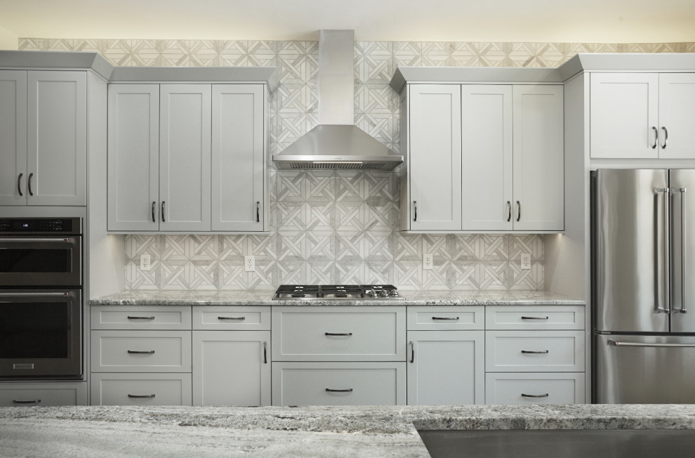 Bild på ett stort funkis grå linjärt grått kök och matrum, med en undermonterad diskho, skåp i shakerstil, blå skåp, granitbänkskiva, grått stänkskydd, stänkskydd i marmor, rostfria vitvaror, laminatgolv, en köksö och brunt golv