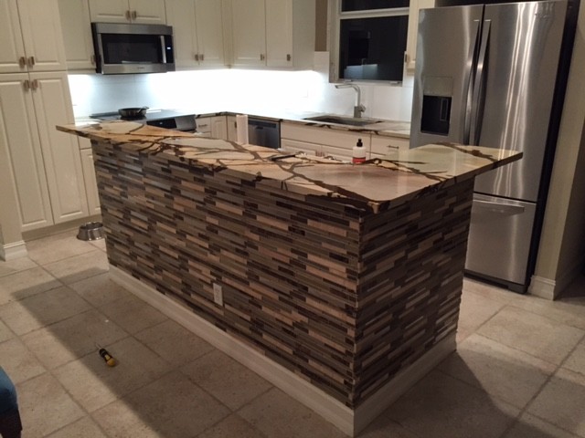 Inspiration for a porcelain tile kitchen remodel in Miami with an undermount sink, granite countertops, white backsplash, porcelain backsplash, stainless steel appliances and an island