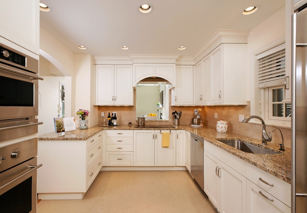 This is an example of a mid-sized traditional u-shaped separate kitchen in DC Metro with an undermount sink, shaker cabinets, white cabinets, granite benchtops, beige splashback, stone tile splashback, stainless steel appliances, laminate floors and a peninsula.