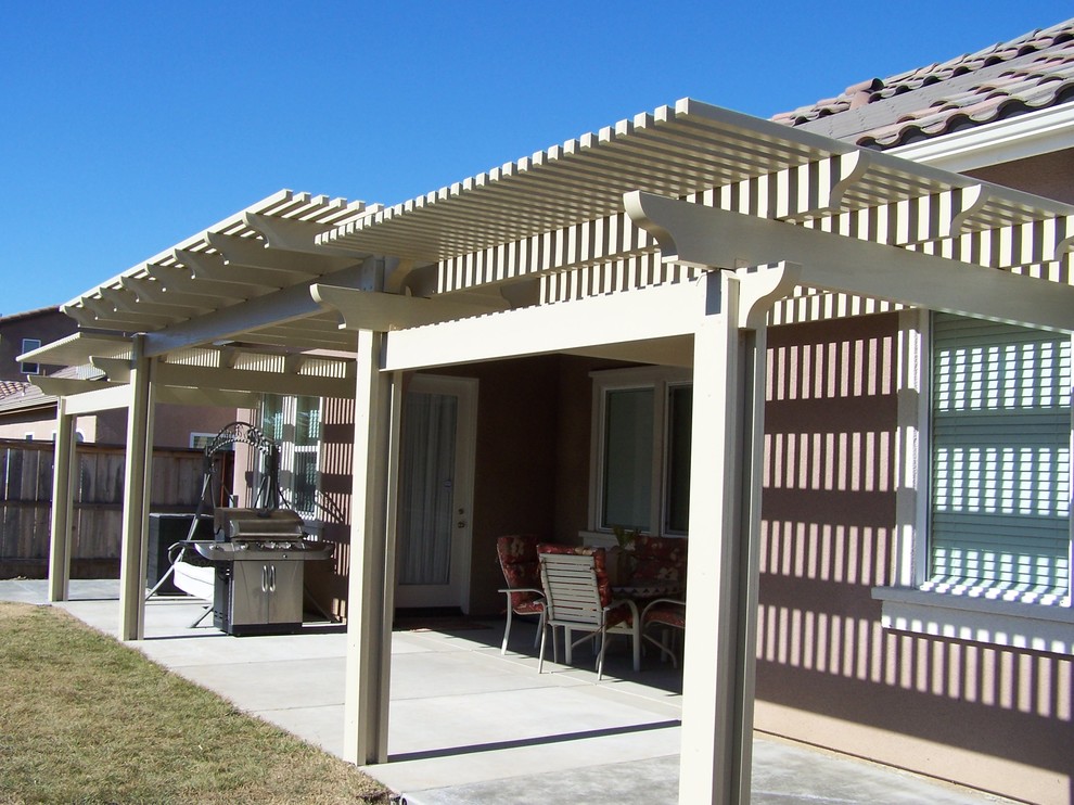 Example of a mid-sized classic backyard concrete patio kitchen design in Other with a pergola