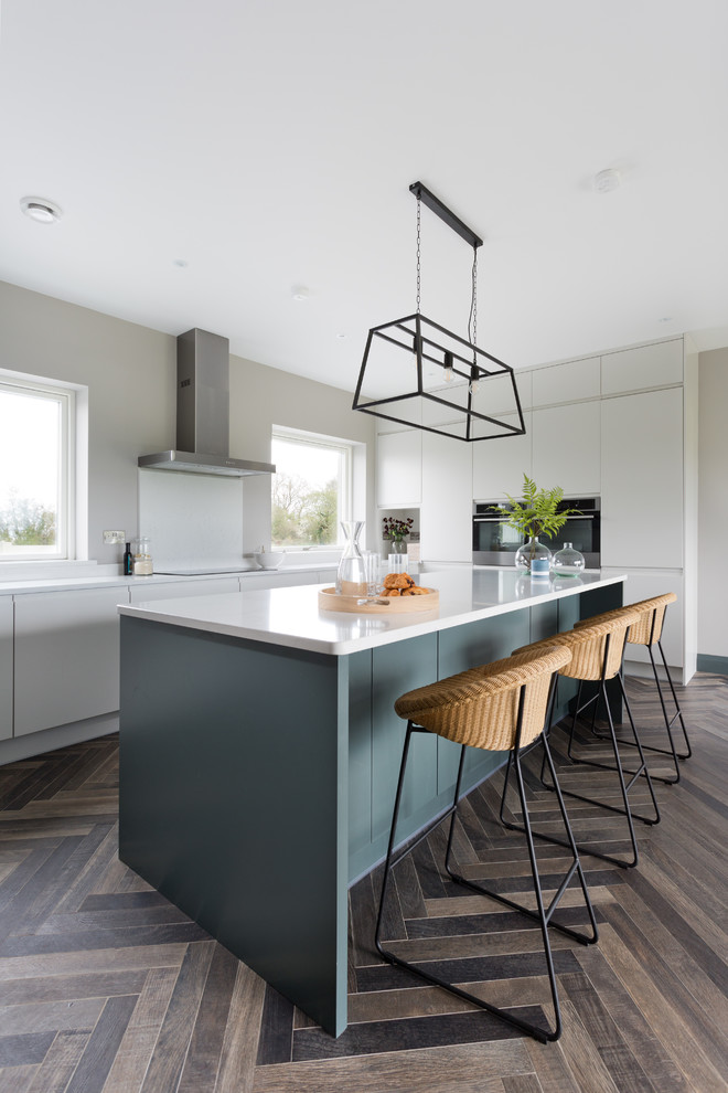 Large contemporary l-shaped eat-in kitchen in Cork with an undermount sink, flat-panel cabinets, grey cabinets, quartzite benchtops, white splashback, glass sheet splashback, stainless steel appliances, ceramic floors, with island, brown floor and white benchtop.