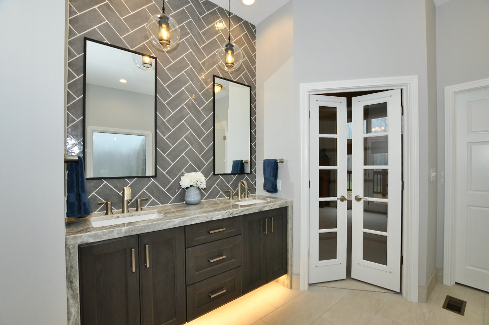 Photo of a large modern master bathroom in Indianapolis with shaker cabinets, black cabinets, a freestanding tub, an alcove shower, a two-piece toilet, gray tile, ceramic tile, white walls, ceramic floors, an undermount sink, marble benchtops, beige floor, a hinged shower door, grey benchtops, a double vanity and a floating vanity.