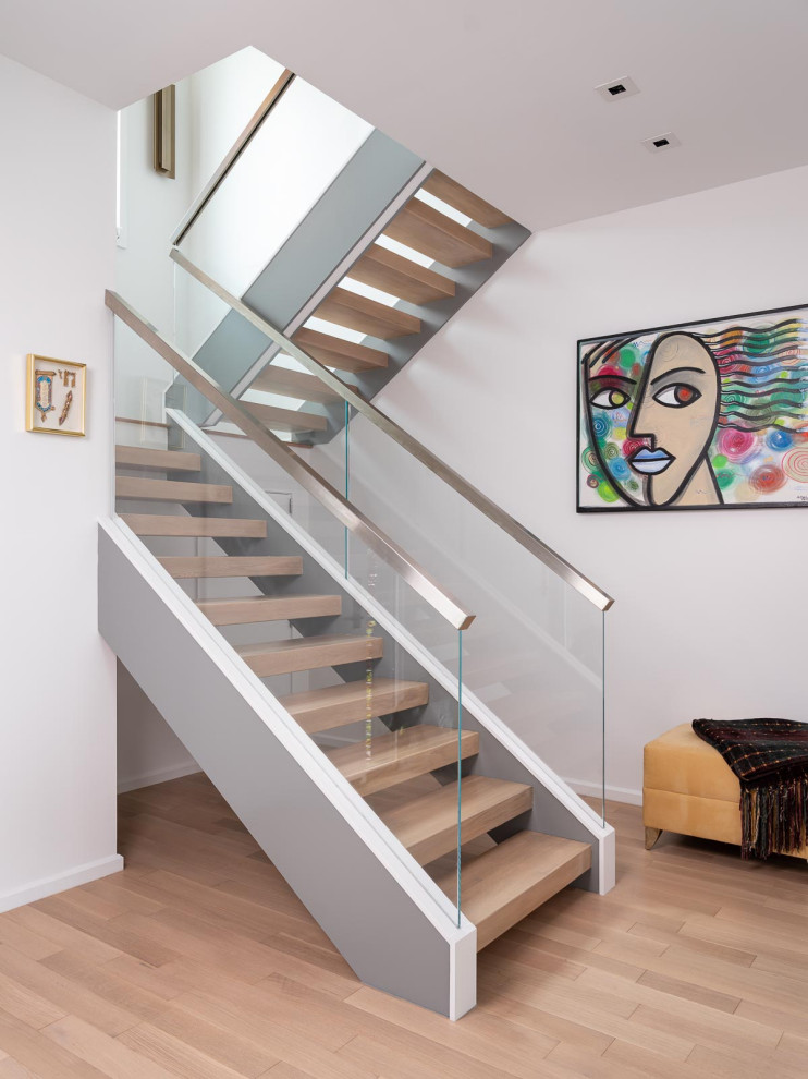 Photo of a contemporary wood u-shaped staircase in New York with glass railing and open risers.