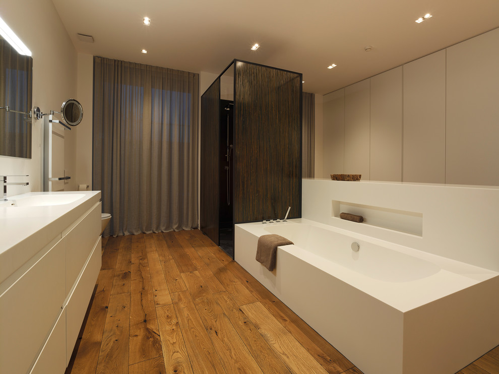 Design ideas for a contemporary bathroom in Other with flat-panel cabinets, white cabinets, medium hardwood floors, an integrated sink, a drop-in tub and a curbless shower.