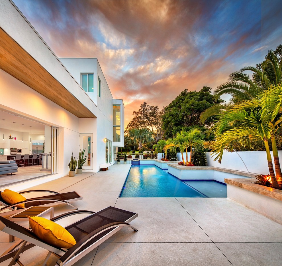 This is an example of a mid-sized contemporary custom-shaped pool in Tampa with concrete slab.