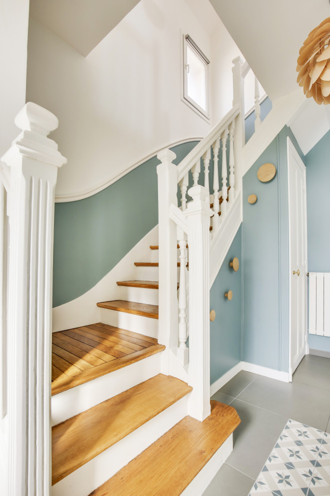Пример оригинального дизайна: изогнутая лестница среднего размера в скандинавском стиле с деревянными ступенями, крашенными деревянными подступенками, деревянными перилами и панелями на стенах