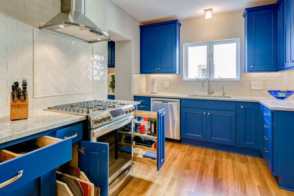 Kitchen - transitional light wood floor kitchen idea in Columbus with an undermount sink, recessed-panel cabinets, blue cabinets, marble countertops, white backsplash and stainless steel appliances