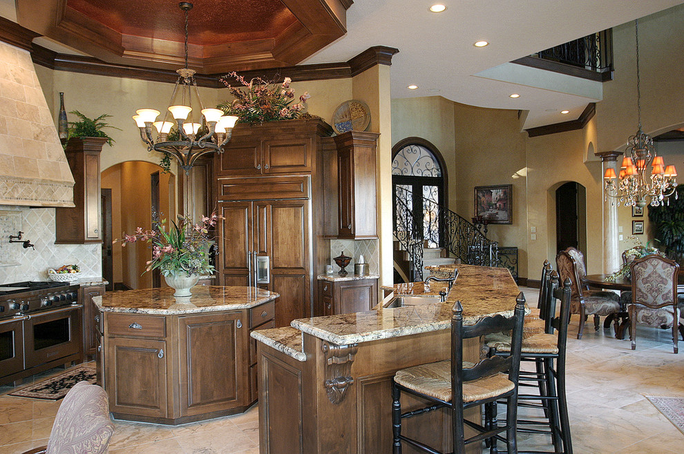 Photo of a large mediterranean open plan kitchen in Houston with an undermount sink, raised-panel cabinets, medium wood cabinets, granite benchtops, grey splashback, cement tile splashback, panelled appliances, travertine floors and with island.