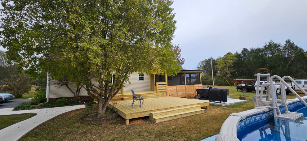 Cette photo montre une grande terrasse arrière et au rez-de-chaussée nature avec une extension de toiture et un garde-corps en bois.