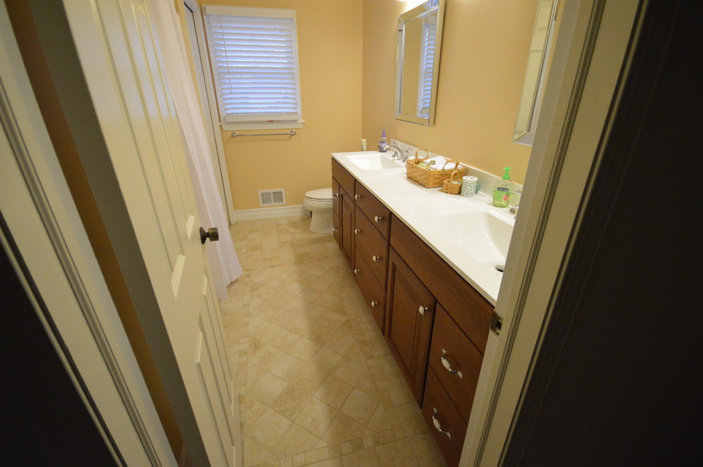 This is an example of a mid-sized traditional bathroom in Detroit with an integrated sink, raised-panel cabinets, dark wood cabinets, a two-piece toilet, beige tile, ceramic floors, a shower/bathtub combo, an alcove tub, ceramic tile and yellow walls.