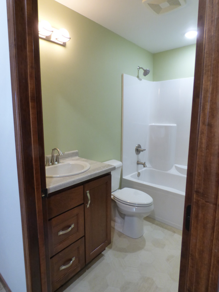 Medium sized classic family bathroom in Other with flat-panel cabinets, dark wood cabinets, an alcove bath, a shower/bath combination, a one-piece toilet, green walls, lino flooring, a built-in sink, laminate worktops, beige floors, a shower curtain, beige worktops, a single sink and a built in vanity unit.