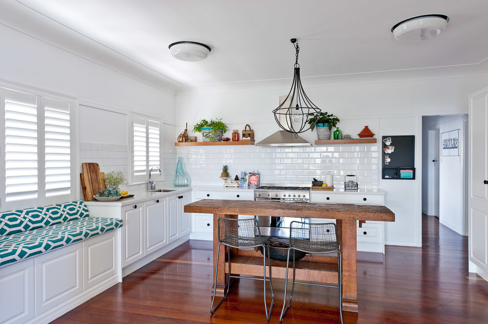 Design ideas for a mid-sized country l-shaped eat-in kitchen in Brisbane with an undermount sink, raised-panel cabinets, white cabinets, granite benchtops, white splashback, subway tile splashback, stainless steel appliances, dark hardwood floors and with island.