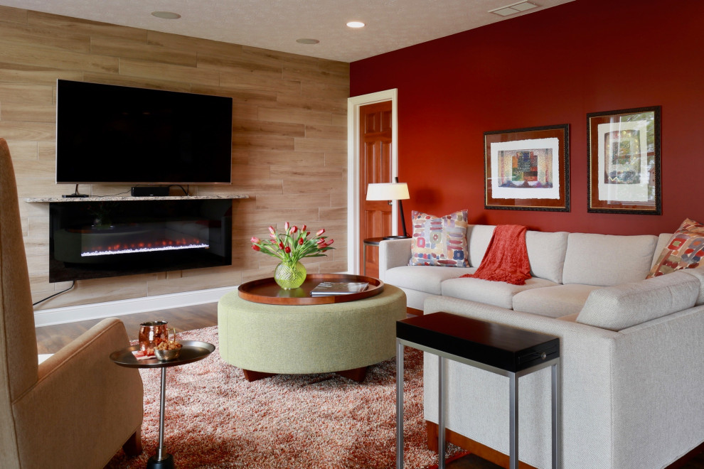 Modern inredning av ett stort allrum med öppen planlösning, med röda väggar, mellanmörkt trägolv, en hängande öppen spis, en fristående TV och brunt golv
