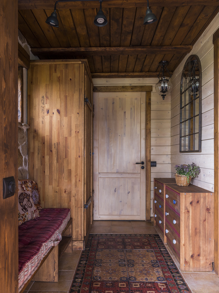 Inspiration for a mid-sized country vestibule in Moscow with beige walls, porcelain floors, a single front door, a brown front door and red floor.