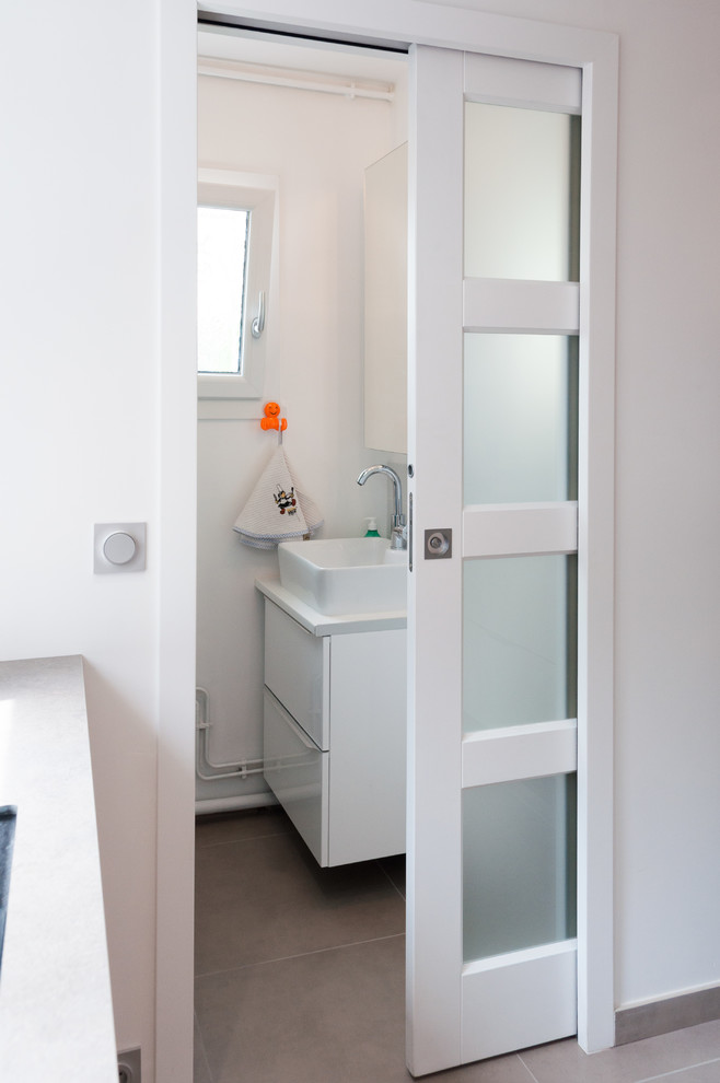 This is an example of a small contemporary single-wall utility room in Lyon with a drop-in sink, ceramic floors and grey floor.