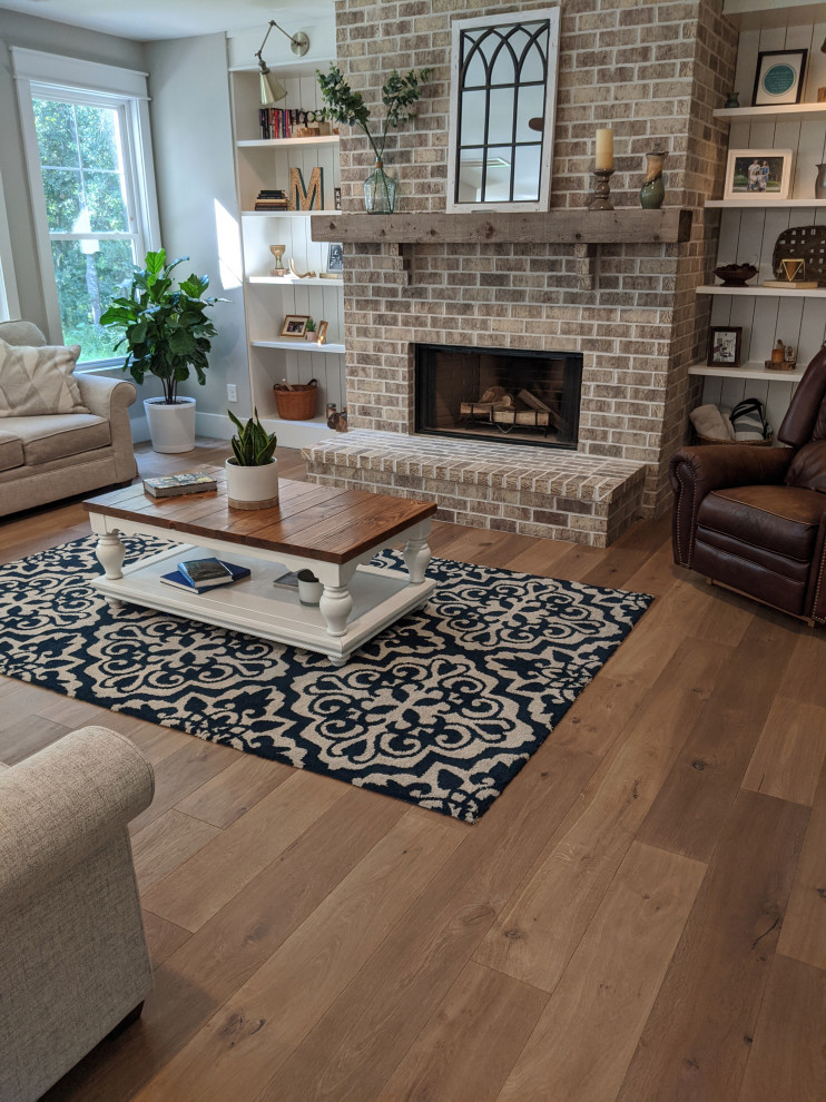 Open concept living room in Charleston with grey walls, medium hardwood floors, a standard fireplace, a brick fireplace surround and beige floor.