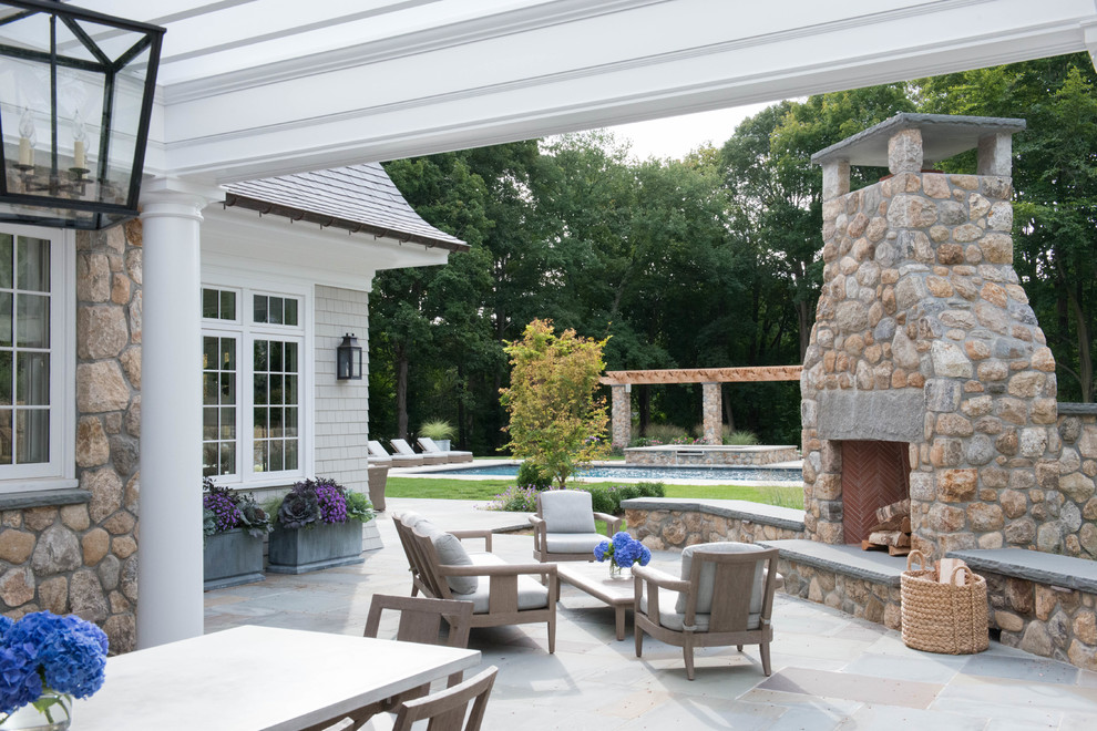 This is an example of a large traditional backyard patio in New York with tile and a roof extension.