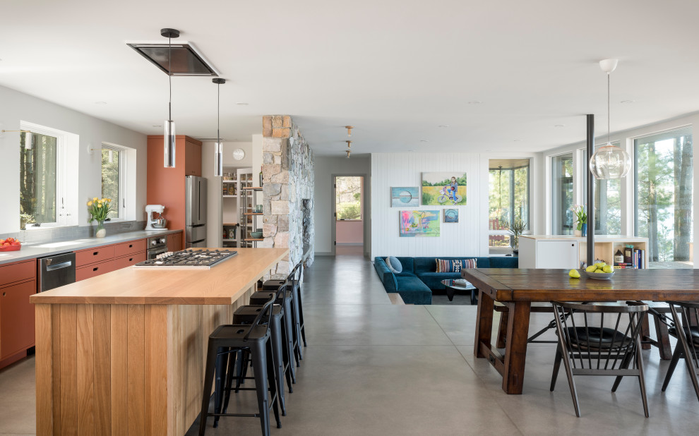Idéer för att renovera ett mellanstort funkis brun brunt kök med öppen planlösning, med en undermonterad diskho, släta luckor, orange skåp, kaklad bänkskiva, grått stänkskydd, stänkskydd i glaskakel, rostfria vitvaror, betonggolv, en köksö och grått golv