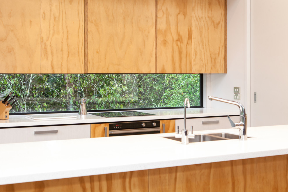 Photo of a small contemporary galley eat-in kitchen in Dunedin with an undermount sink, flat-panel cabinets, light wood cabinets, solid surface benchtops, stainless steel appliances, with island and white benchtop.
